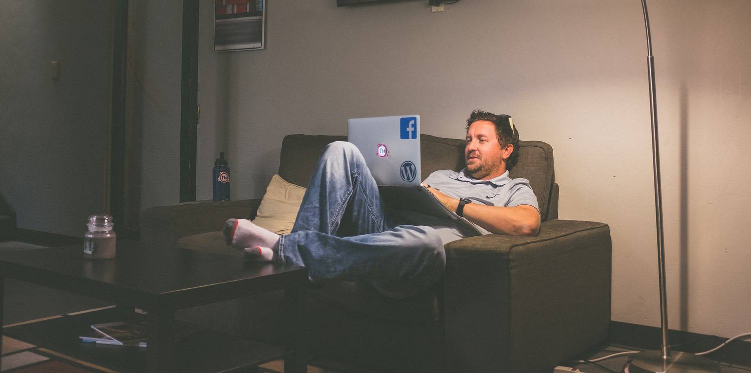 A man sitting on a couch with his laptop